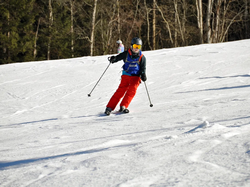 Skifahrer in roter Hose auf der sonnigen Piste.